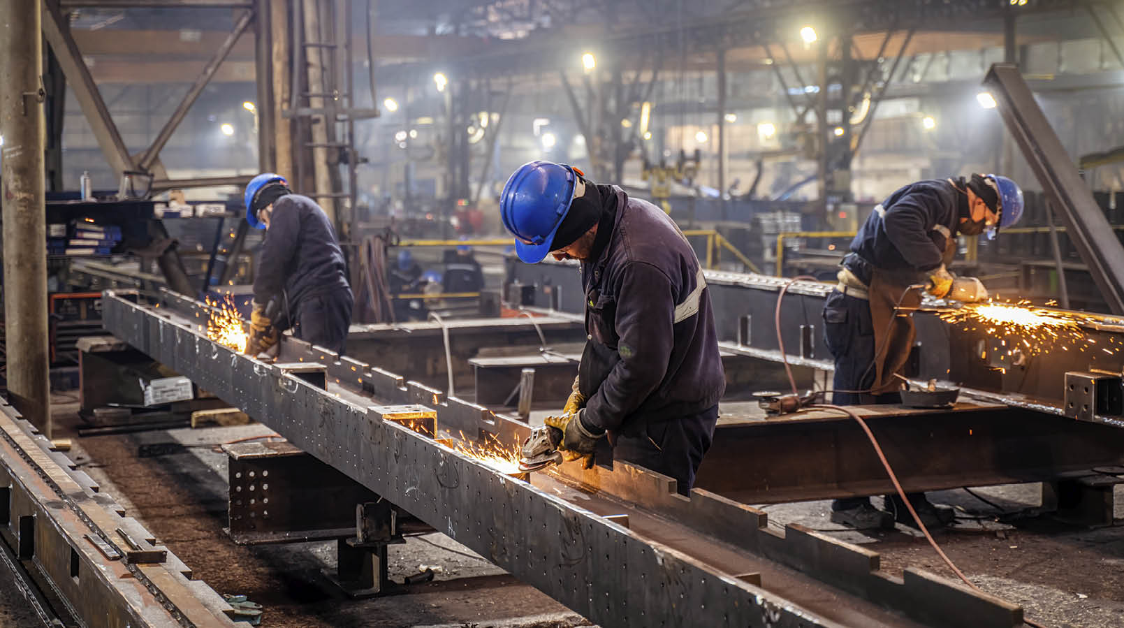 Metal workers using a grinder