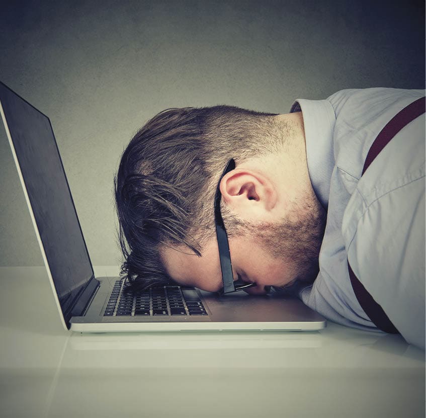 Side view of chubby man looking broken while lying on top of laptop.
