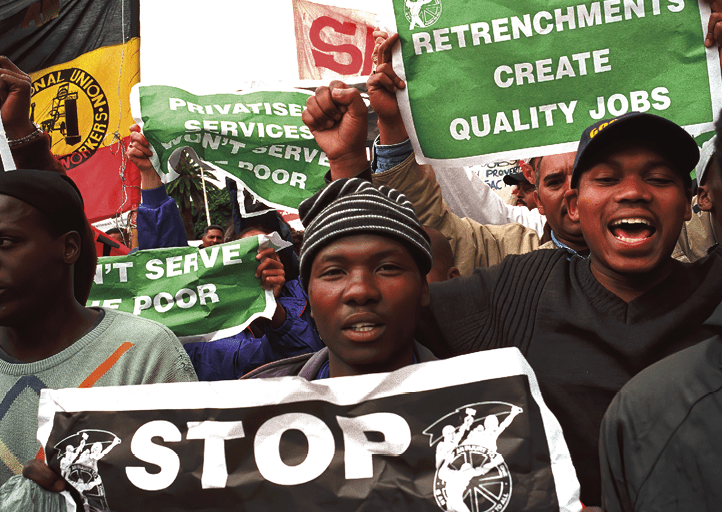 CAPE TOWN, SOUTH AFRICA - OCTOBER 1: People shout and carry signs during a demonstration against privatization and poverty on October 1, 2002 in central Cape Town, South Africa. The SA Trade Unions (COSATU) staged a two-day demonstration against the (ANC) African National Congress governments privatization of state companies economic policies. South Africa's unemployment rate is about 40 percent and they are struggling with high inflation and a weak currency that is hurting the poor.  (Photo by Per-Anders Pettersson/Getty Images) 