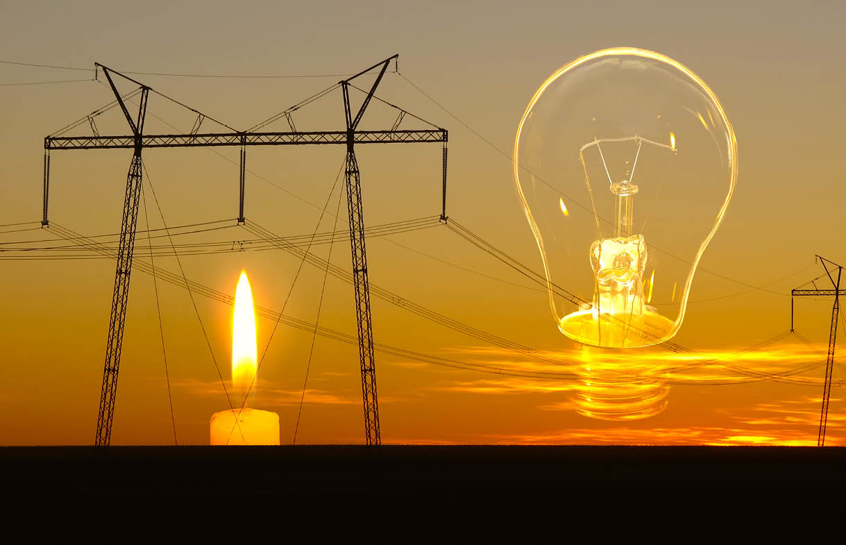 Burning candle, unlit light bulb and disconnected power lines on evening sky background. Energy outage and blackout. Energy crisis.