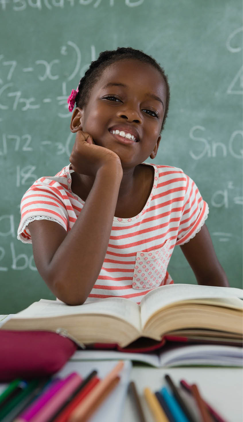 Portrait of schoolgirl reading book in classroom