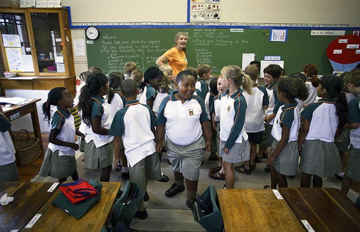 CAMPS BAY, SOUTH AFRICA - JANUARY 17: Siphumle Mwandaba (c), age 7, gets instructions from his new teacher as he attends Grade 1 first day of school with his new friends at Camps Bay Preparatory School on January 17, 2007 in Camps Bay, an affluent suburb of Cape Town, South Africa. The seaside suburb is one of the most affluent in the country and the school has a good record racial mix. (Photo by Per-Anders Pettersson/Getty Images)