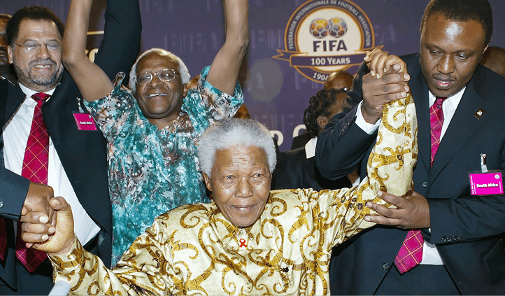 ZURICH, SWITZERLAND ? MAY 15: Former South African President Nelson Mandela (C) is helped by Bid Chairman Irvin Khoza as Danny Jordaan and Archbishop Desmond Tutu look on during the FIFA 2010 World Cup Host Announcement at the World Trade Centre on May 15, 2004 in Zurich, Switzerland.  (Photo by Touchline/Getty Images)