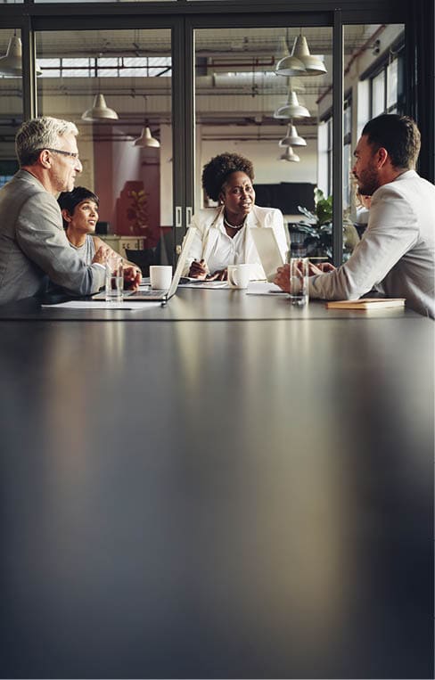 African American businesswoman sitting with her diverse team around a table in an office boardroom discussing work
