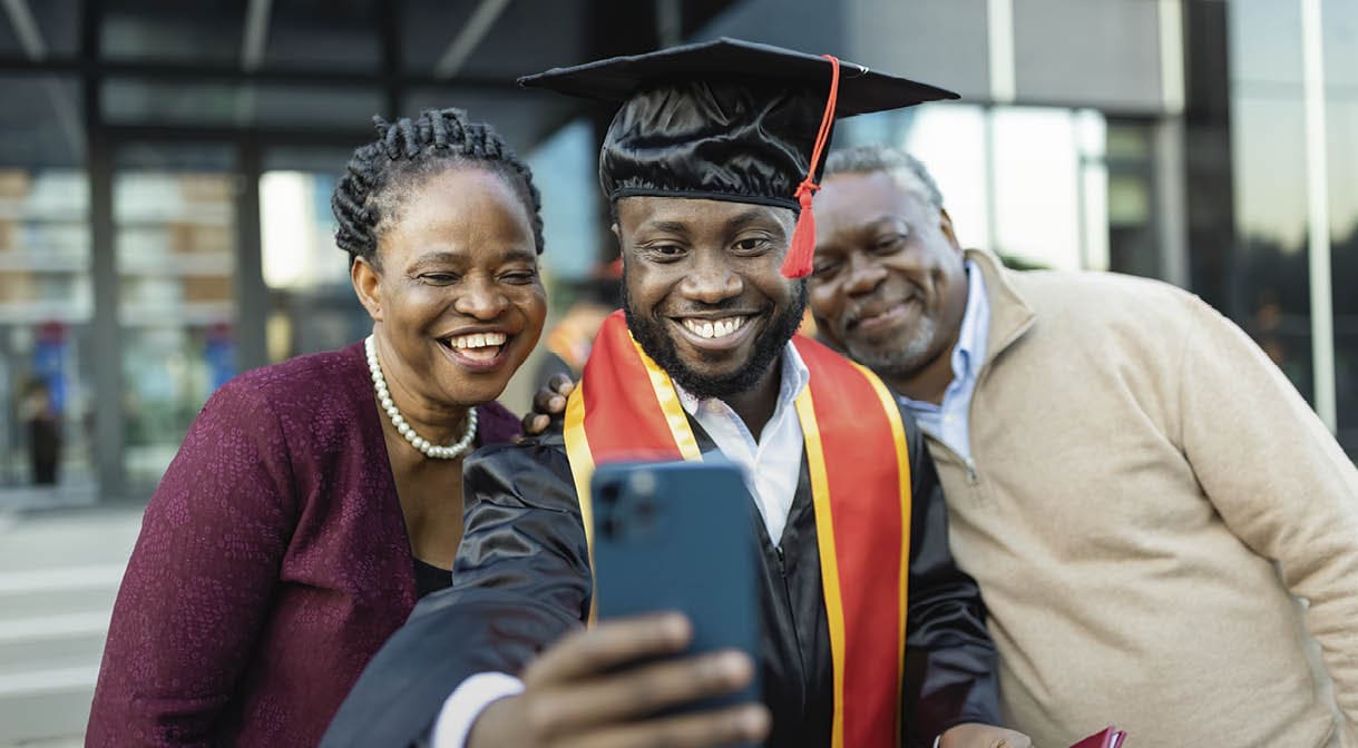 Excited African American college graduate with his family after the graduation ceremony taking selfie