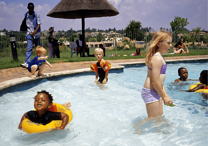 JOHANNESBURG, SOUTH AFRICA - FEBRUARY 29: (.). Lebone Dube, 4 (far R), playis in a swimming pool with her friends at her birthday party on February 29, 2004 in Cedar Lake, an upper class gated community in Johannesburg, South Africa. Her father, Oscar Dube, works as a Key Account manager for the Swedish mobile phone equipment maker Ericsson and his wife, Mpho Dube, is fund manager at Old Mutual, an insurance company in South Africa. They belong to the new black elite in South Africa. Lebone attends an exclusive pre-school with mostly white children and she invited them for her birthday party. Well educated and connected, they have risen from the poverty in the townships to a very different lifestyle, since the fall of Apartheid and the start of democracy in the country in 1994. (Photo by Per-Anders Pettersson/Getty Images)