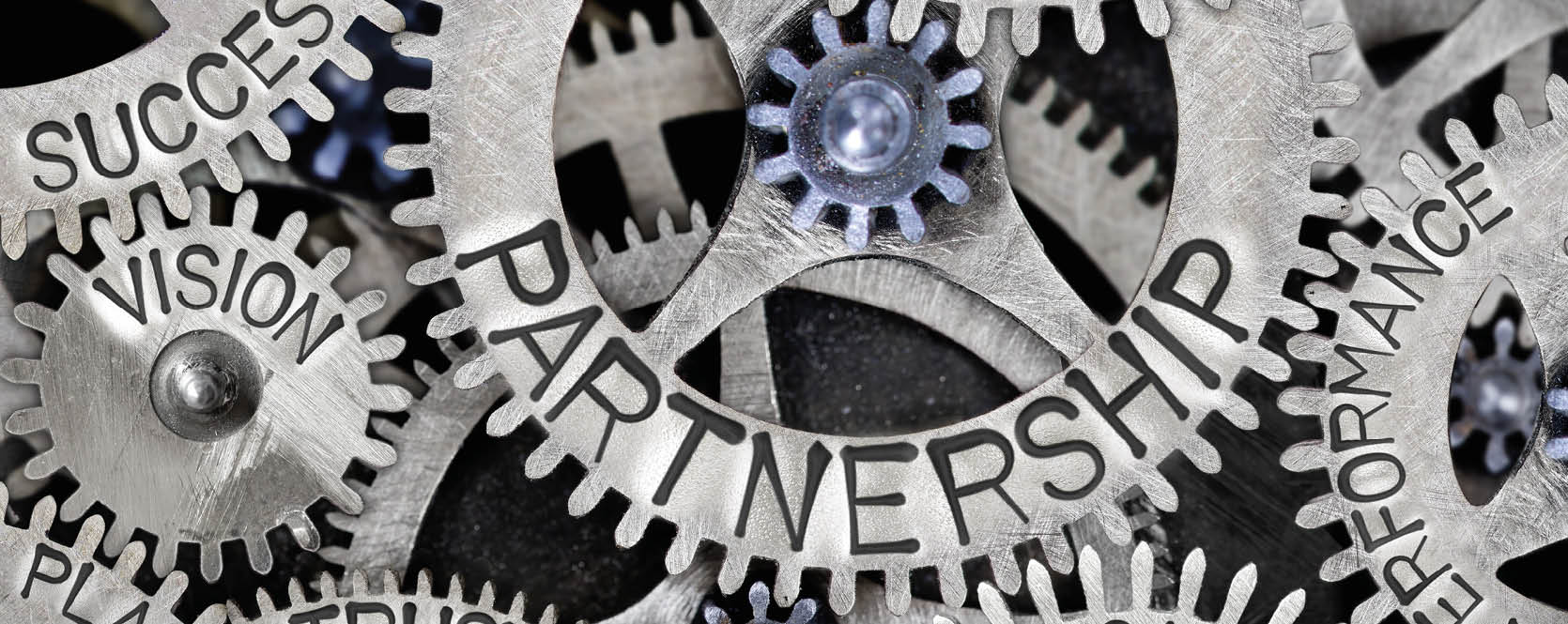 Macro photo of tooth wheel mechanism with Partnership related words imprinted on metal surface