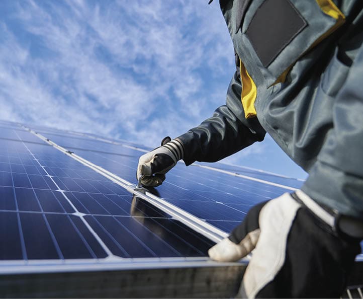 Close up of man technician in work gloves installing stand-alone photovoltaic solar panel system under beautiful blue sky with clouds. Concept of alternative energy and power sustainable resources.