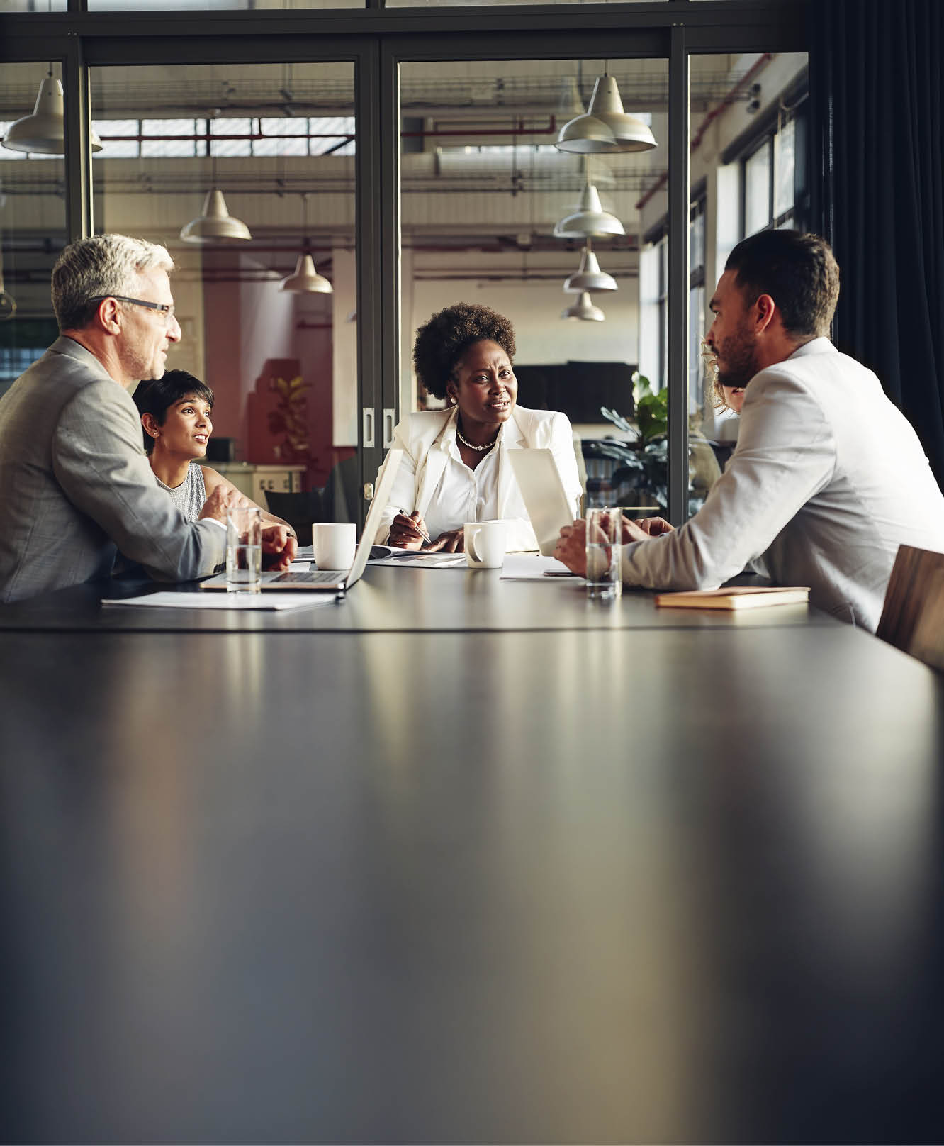 African American businesswoman sitting with her diverse team around a table in an office boardroom discussing work