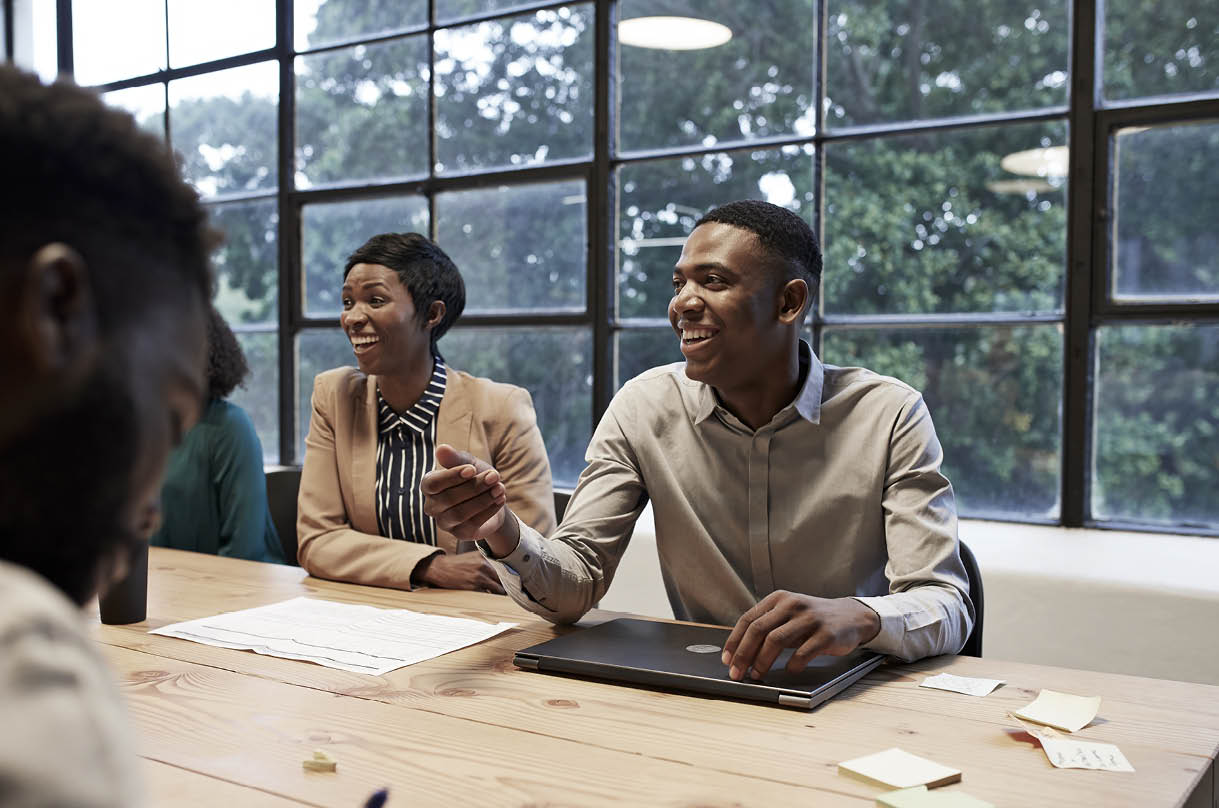 Smiling business colleagues sitting in conference room during office meeting at workplace