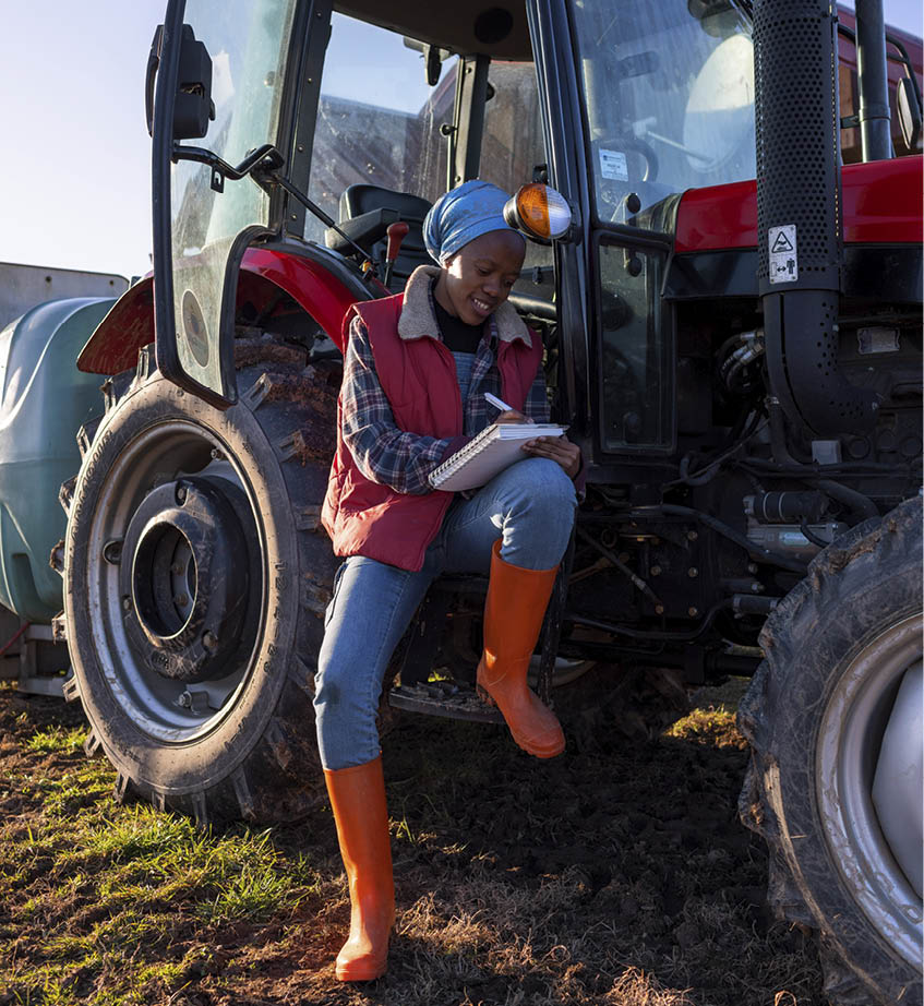 Young female farmer writing a work report. She is sitting in the tractor and writing.