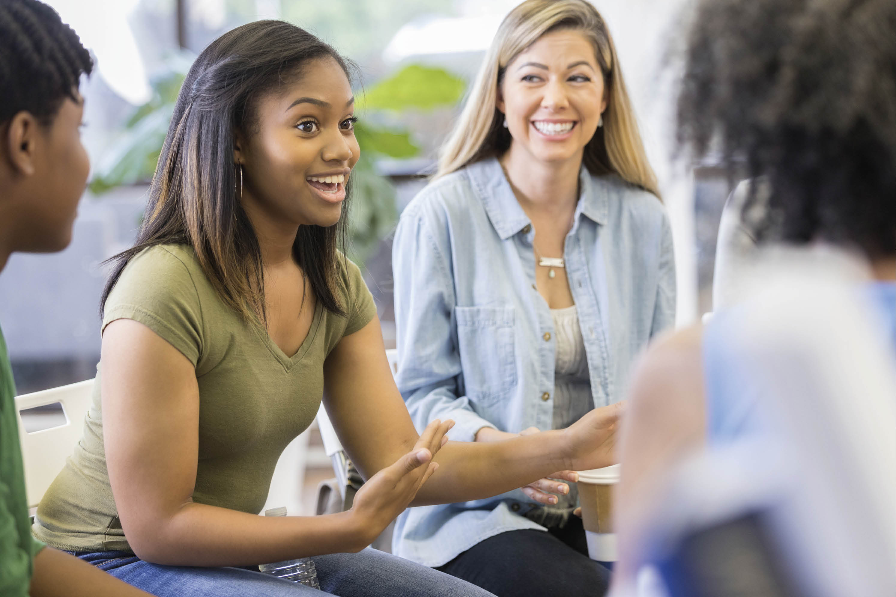 Teenage girl gestures as she discusses something during a support group or group therapy session.
