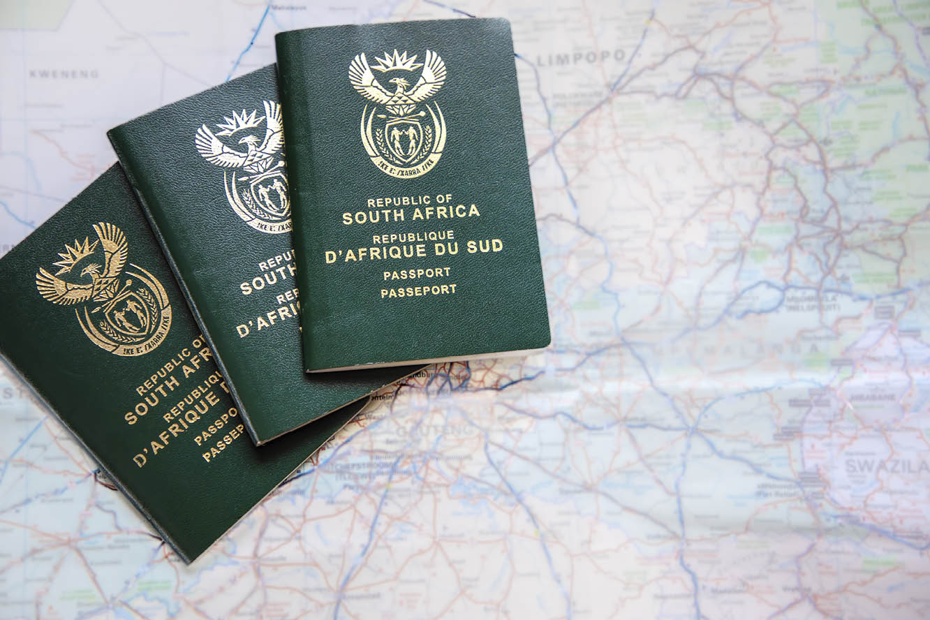 Three South African passports agains a  out of focus map of South Africa  Concept for covid travel restrictions and travel ban