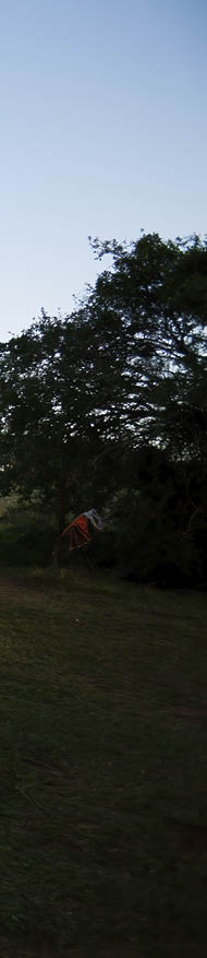 A rural African woman and her child standing in front of their house 