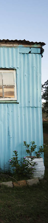 A rural African woman and her child standing in front of their house 