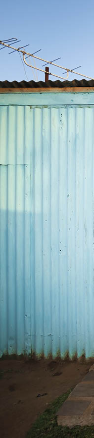 A rural African woman and her child standing in front of their house 