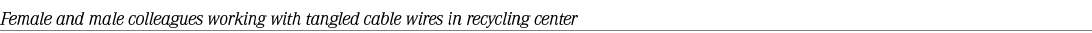 Female and male colleagues working with tangled cable wires in recycling center 