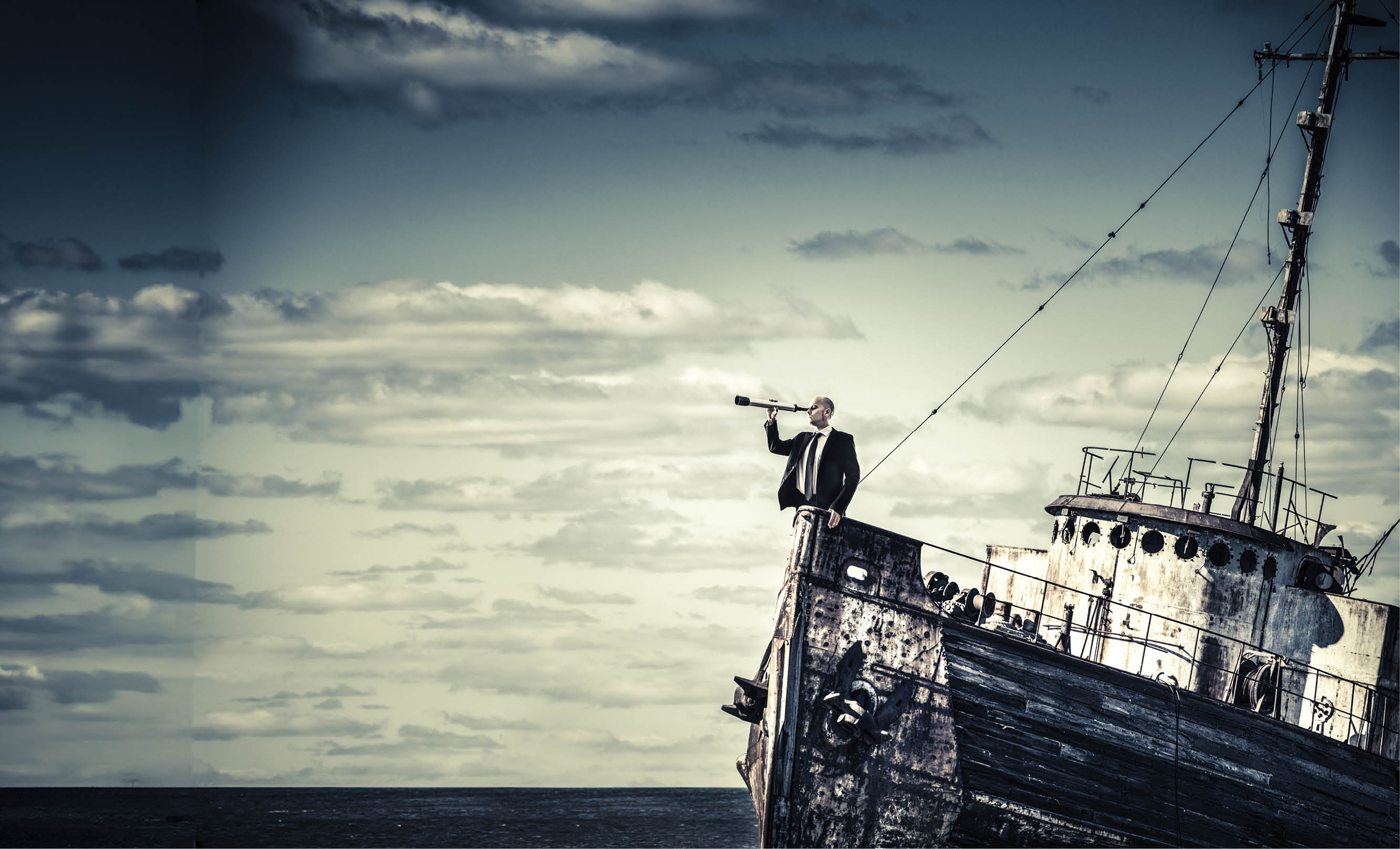 Businessman looking through spyglass from sinking shipwreck.